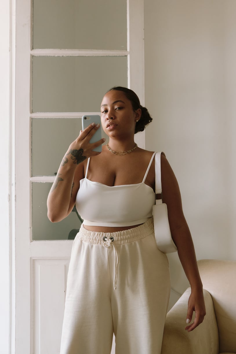 Woman in White Outfit with Bag Taking Selfie Indoors