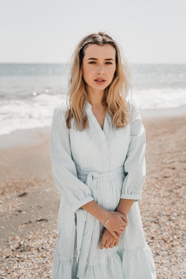 Pensive young female on seashore in sunny day